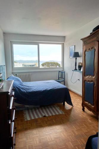 une chambre avec un lit et une grande fenêtre dans l'établissement Belle vue mer pour ce T3 à la ciotat, à La Ciotat