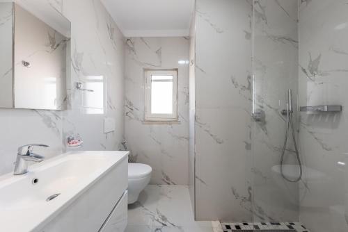 La salle de bains blanche est pourvue d'un lavabo et de toilettes. dans l'établissement Sea View Apartments ELDO, à Durrës