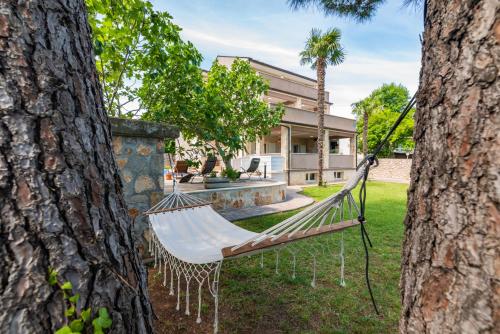 a hammock in a yard between two trees at Private Villa SoulSet with swimming pool in Vantačići