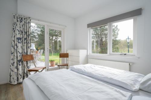 a white bedroom with a bed and a window at Luxe Villa Texel 8-10 personen met Sauna Krim 95 in De Cocksdorp
