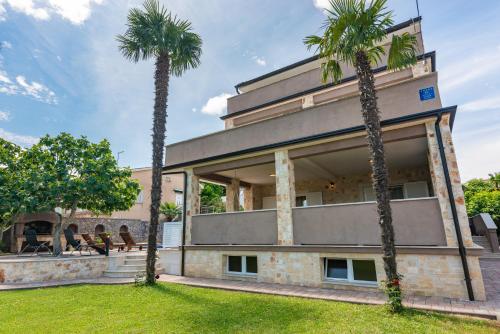 two palm trees in front of a building at Private Villa SoulSet with swimming pool in Vantačići
