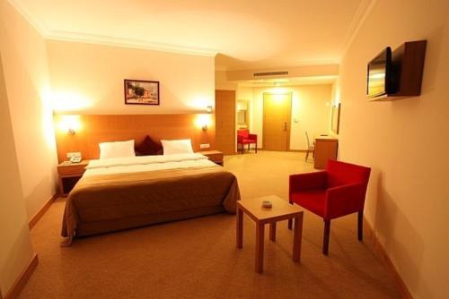 Shilla Hotel في فليميشه: غرفة بالفندق سرير وكرسي احمر
