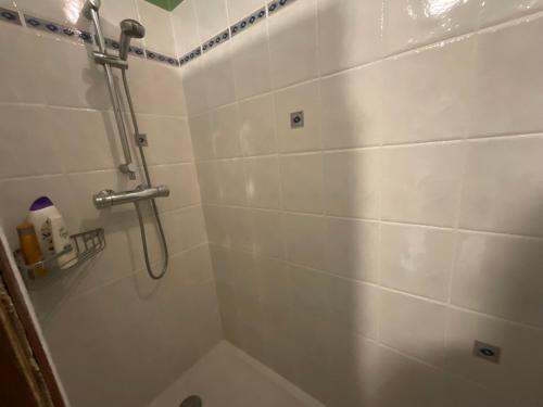 La salle de bains est pourvue d'une douche et d'un mur carrelé blanc. dans l'établissement La Belle Brise des Oliviers, à Saint-Ambroix