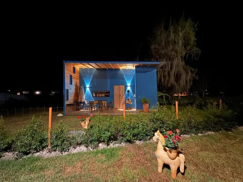 Uma pequena casa azul com dois cavalos falsos à frente. em Corinto Tiny House em Paipa