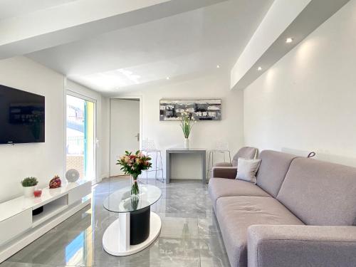 a living room with a couch and a table at Luxury "Les Toits du Soleil" - Magnifique appartement avec terrasses et jacuzzi - Centre de cannes - By SCLS Locations in Cannes