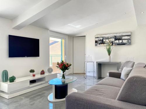 a living room with a couch and a tv on a wall at Luxury "Les Toits du Soleil" - Magnifique appartement avec terrasses et jacuzzi - Centre de cannes - By SCLS Locations in Cannes