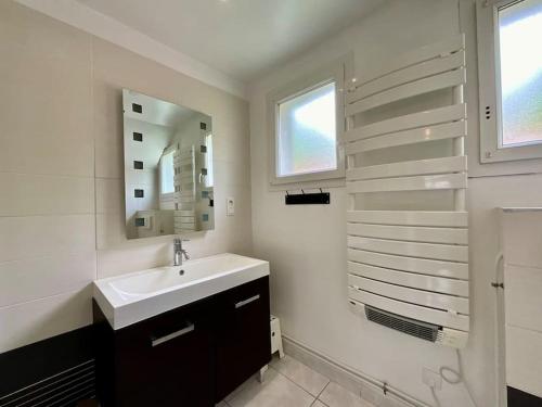 une salle de bain blanche avec un lavabo et un miroir dans l'établissement L'Appart du Lac de Gérardmer - Beau & spacieux, à Gérardmer