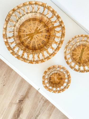 a set of four rattan plates on a white wall at Apartamento Luar by ALÔGA in Cee