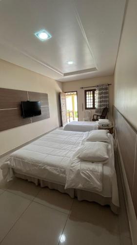 a large bedroom with two beds and a flat screen tv at Hotel Fazenda Ceu Aberto in Gravatá