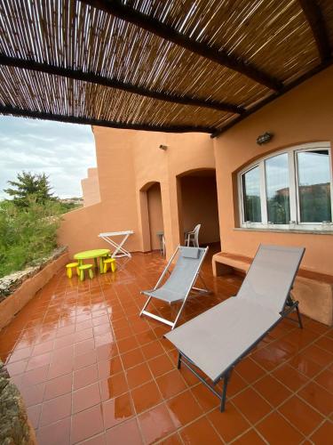 a patio with two chairs and a table at Appartamento Calarossa Sardegna CasaRosa in Isola Rossa