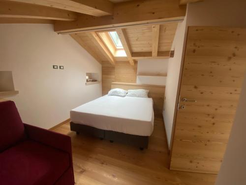 Habitación pequeña con cama y silla roja. en Chalet Le Grazie en Le Grazie