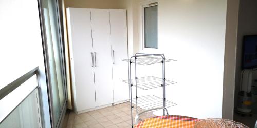 une étagère métallique dans une pièce avec une armoire blanche dans l'établissement Le California, à Cagnes-sur-Mer