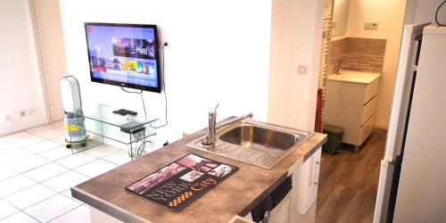 Il comprend une cuisine avec un évier et une télévision murale. dans l'établissement Le California, à Cagnes-sur-Mer