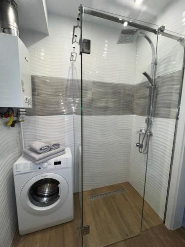 a shower stall with a washing machine in a bathroom at Apartament Sunrise in Częstochowa