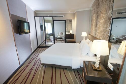a bedroom with a white bed and a living room at Dorsett Kuala Lumpur in Kuala Lumpur