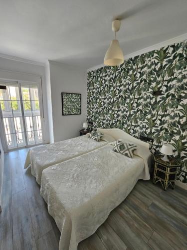 Un dormitorio con 2 camas y una pared con plantas. en Pedregalejo Beach House, en Málaga