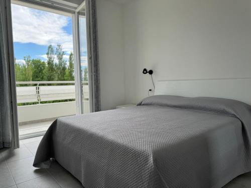Un dormitorio con una cama y una ventana grande. en Residence Riva del Mulino, en Marina di Montenero