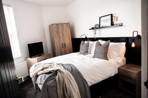 una camera da letto con letto, lenzuola e cuscini bianchi di Urban Loft Apartment • 2 Bedroom • Manchester ad Ashton under Lyne