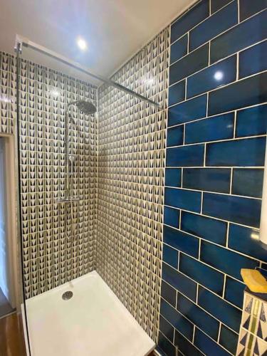 La salle de bains est pourvue d'une douche et d'un mur en carrelage bleu. dans l'établissement Terra Élégant appartement Gare SNCF 4p, à Clermont-Ferrand
