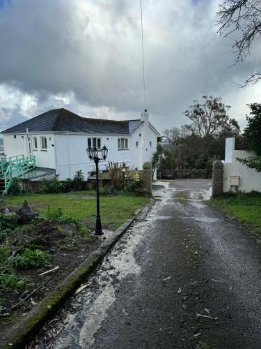 a white house with a street light on the side of a road at Shan Mu Inn Entire flat 2 bedrooms with terrace seaview in Newlyn