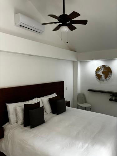 a bedroom with a white bed with a ceiling fan at VILLAS EL ENCANTO in Jalpan