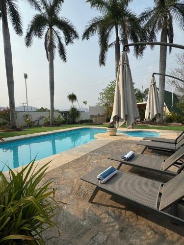 a pool with two lounge chairs and an umbrella at VILLAS EL ENCANTO in Jalpan de Serra
