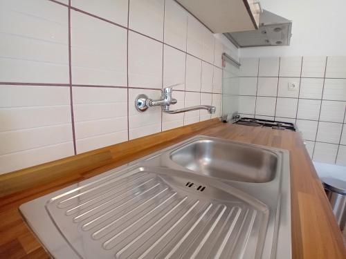 un fregadero de acero inoxidable en una cocina con azulejos blancos en Apartments Angie, en Zadar
