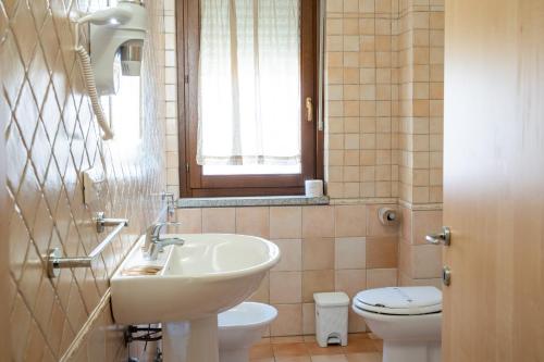 a bathroom with a sink and a toilet and a window at Appartamenti Le Vele in La Maddalena