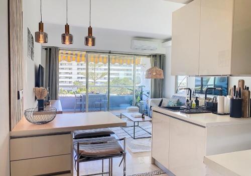 une cuisine avec des armoires blanches et un salon dans l'établissement T1bis vue mer et port Marina Baie des Anges, à Villeneuve-Loubet