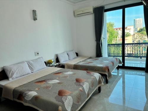 two beds in a room with a balcony at Khách Sạn Tuấn Thảo Cửa Lò in Cửa Lò
