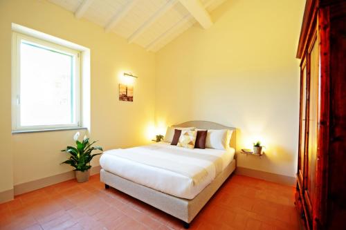 a bedroom with a large white bed and a window at Maremma 1851 in Follonica