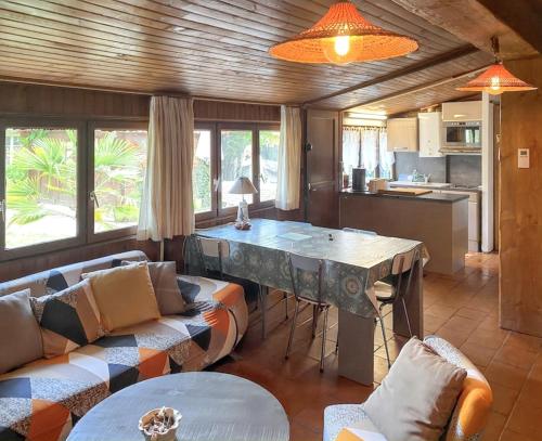 eine Küche und ein Wohnzimmer mit einem Tisch und Sofas in der Unterkunft Maison de 3 chambres avec jardin clos et wifi a Vendays Montalivet a 7 km de la plage in Vendays-Montalivet
