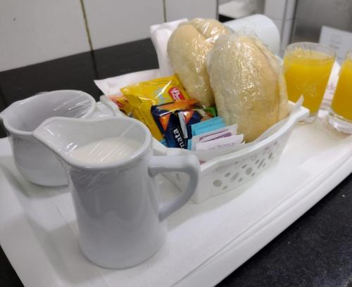 een dienblad met een mandje brood en sinaasappelsap bij Prestige Motel 2 in Curitiba