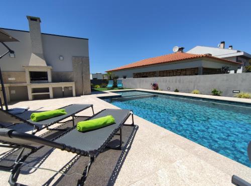 a swimming pool with two lounge chairs next to a house at Antas Villa Family in Esposende