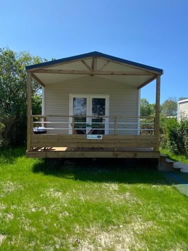 a small house with a large deck on the grass at camping des crocs in Saint-Quentin-en-Tourmont