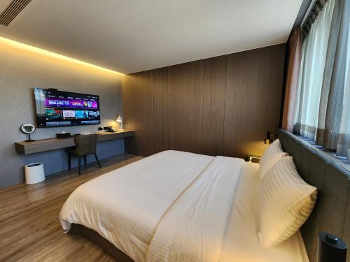 a bedroom with a white bed and a flat screen tv at Hualien Pink Corner Hotel in Hualien City