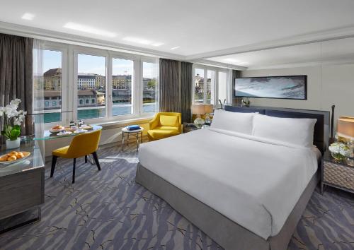 ジュネーヴにあるマンダリン オリエンタル ジュネーブの大きなベッドと大きな窓が備わるホテルルームです。