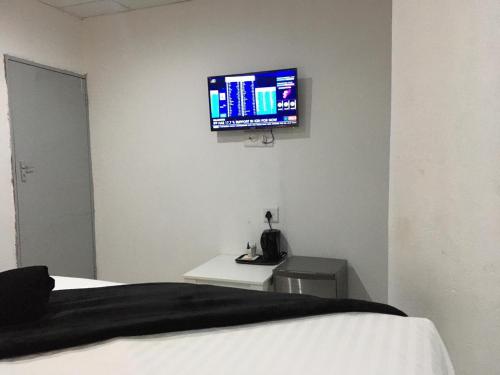 a bedroom with a bed and a flat screen tv on the wall at De Bliss Lodge in Johannesburg