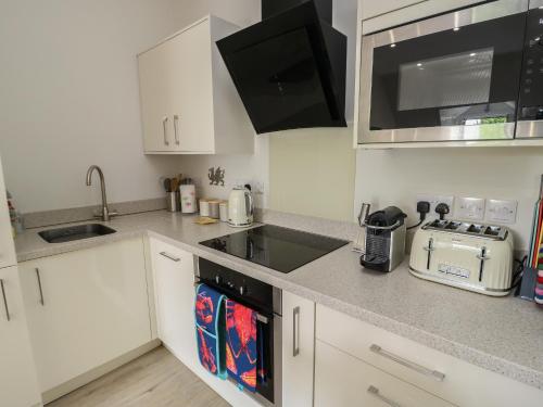 a kitchen with white cabinets and a stove top oven at Sandy Bay Retreat in Benllech
