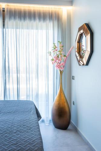 a vase with flowers in a bedroom with a mirror at La Rêve Luxury Apartments in Hersonissos