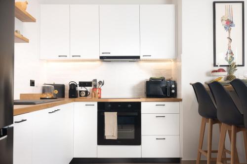 a kitchen with white cabinets and a black oven at Porta Verde Luxury Residence, By TK Property Management in Laganas