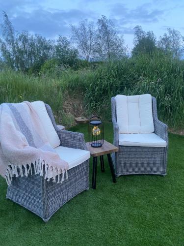 2 Stühle und ein Tisch mit einer Kerze auf dem Gras in der Unterkunft The Nest Quaint Luxury Cottage Getaway in Tiragarvan