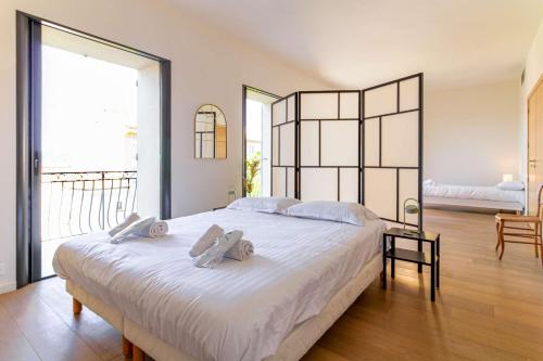a bedroom with a large white bed with towels on it at SELECT'soHOME - Villa pour 8 personnes avec jacuzzi, vue mer et parking au coeur du Lavandou ! - VILLA MOUN PANTAI in Le Lavandou
