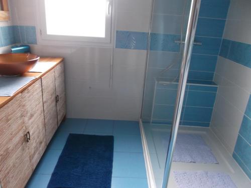 une salle de bain avec douche aux carreaux bleus dans l'établissement LES TROENES, à Ouistreham