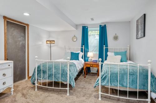 two beds in a bedroom with blue curtains at Lake Front-fishing-all sports Bass Lake Sanctuary in Traverse City