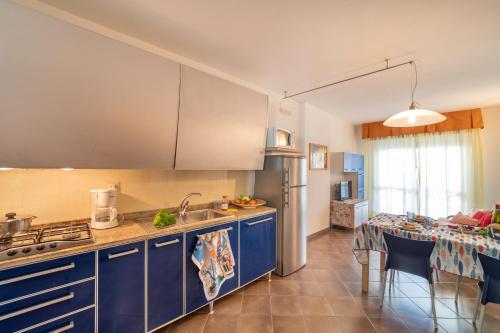 eine Küche mit blauen Schränken und einem Tisch mit Stühlen in der Unterkunft Residenza Al Parco in Bibione