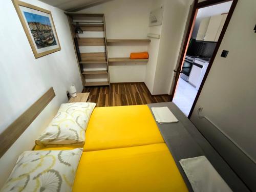 een kleine slaapkamer met een geel bed en een keuken bij Apartmani Andrea in Pula