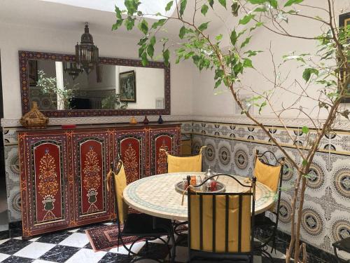een eetkamer met een tafel en een spiegel bij RIAD Lalla Aicha-Qariya Siyahia Marrakech in Marrakesh