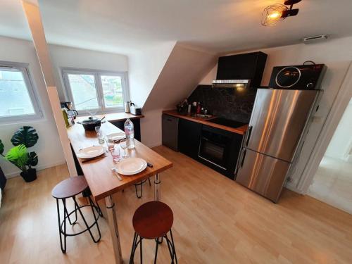 une cuisine avec une table et un réfrigérateur en acier inoxydable dans l'établissement LE MANHATTAN I Neuf I 2 chambres I Proche Mer I Wifi Haut débit, à Saint-Brieuc