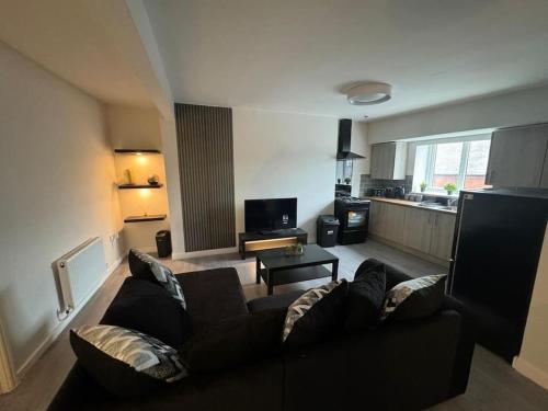 a living room with a black couch and a kitchen at Luxury Apartment in Ramsbottom